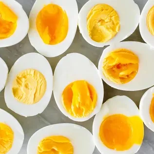 Hard-boiled egg halves on a marble surface, showcasing bright yellow yolks.